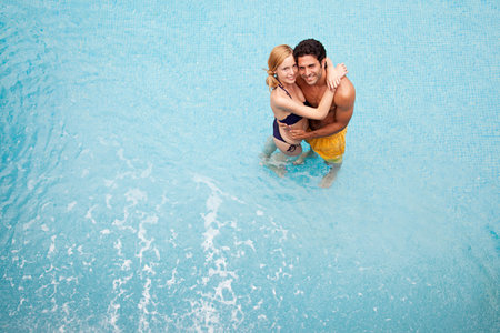 Young couple embracing in swimming pool, high angleの写真素材