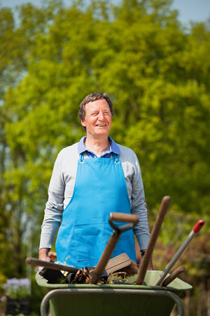 Man pushing wheelbarrow in plant nurseryの写真素材