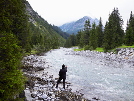 Woman taking pictures of a riverの写真素材