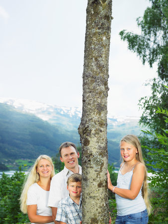Family outdoors by tall tree smilingの写真素材