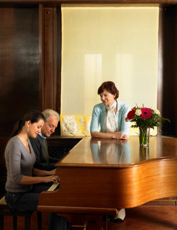 Parents listening to daughter play pianoの写真素材