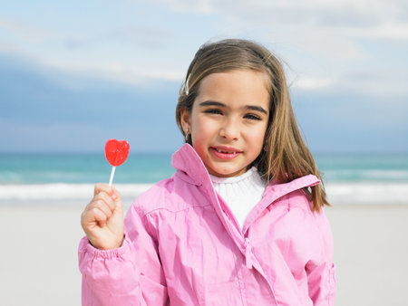Young girl holding lollipop by seaの写真素材