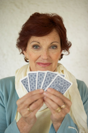 Senior woman holding playing cardsの写真素材