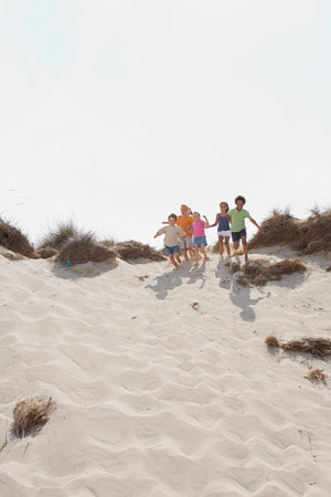 Children running down a duneの写真素材