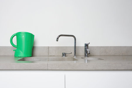 A green kettle next to a sink