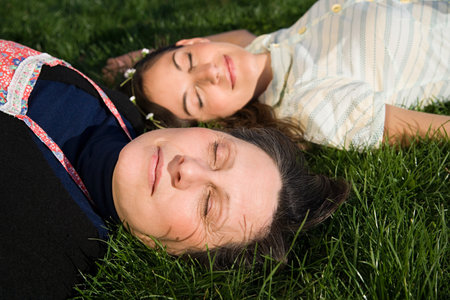 Mother and daughter sleeping on the grassの写真素材