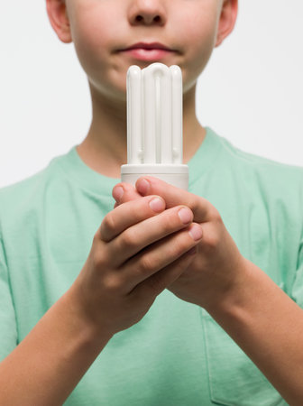 Boy holding an energy saving lightbulbの写真素材