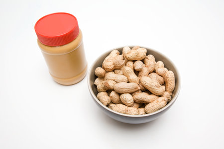 A jar of peanut butter and peanutsの写真素材