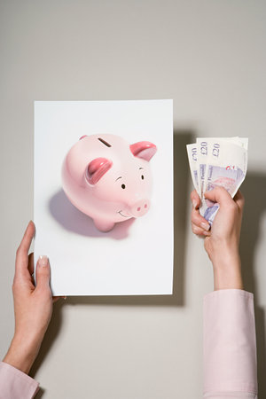 A woman holding a photograph of a piggy bank and moneyの写真素材