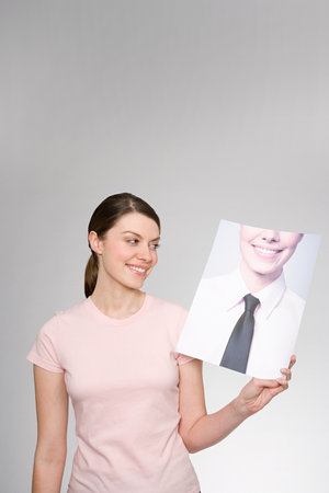 A woman holding a photograph of herselfの写真素材