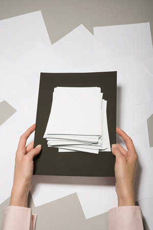 A woman holding a photograph of a stack of paperの写真素材