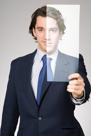 Portrait of a man holding a photograph of himselfの写真素材