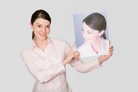 A woman holding a photograph of herselfの写真素材