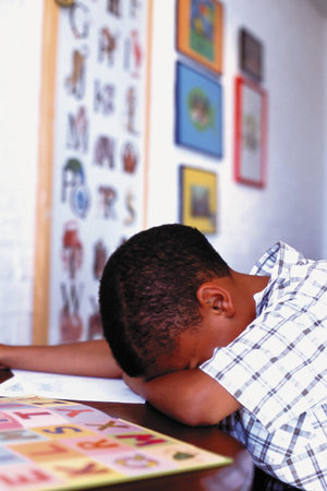 Boy sleeping over homeworkの写真素材