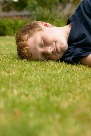 Smiling boy lying on the grassの写真素材
