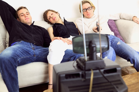 Friends watching television on sofaの写真素材