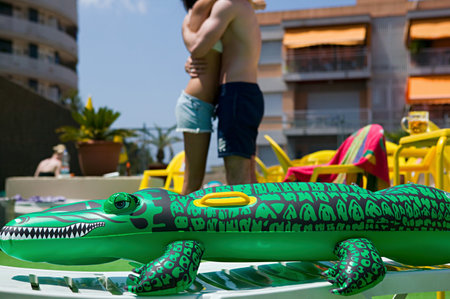 Couple hugging near inflatable crocodileの写真素材