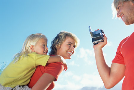 Father filming wife and daughterの写真素材