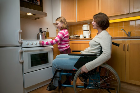 Disabled mother and daughter in kitchenの写真素材