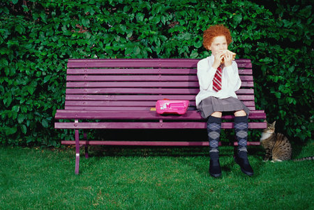 Girl on a bench eating a sandwichの写真素材
