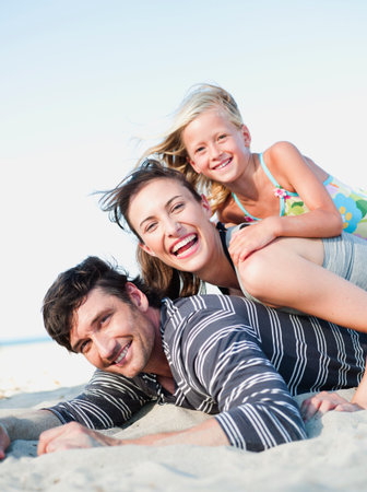 Family Lying In Sand On Beach Smilingの写真素材