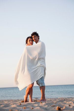 Couple Cuddled Up In Beach Towelの写真素材