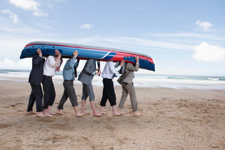 Businessmen Carrying Canoe On Beachの写真素材
