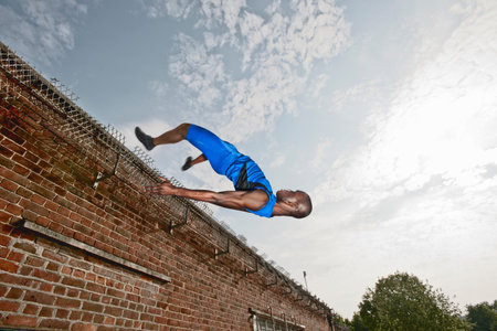 Athlete Vaulting Over Brick Wallの写真素材