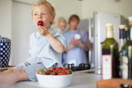 Boy Eating Strawberries On Counterの写真素材