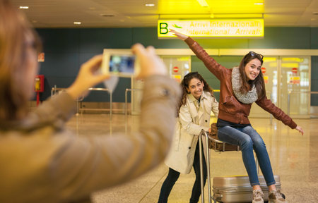 Woman Photographing Two Teenage Girls In Airportの写真素材