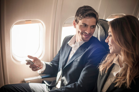 Businesspeople On Aeroplane With Smartphoneの写真素材