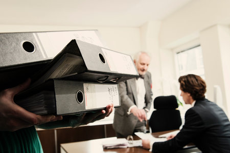 Woman Carrying Ring Binders, Men In Backgroundの写真素材