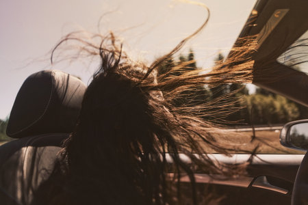 Mid Adult Woman Driving Convertible With Long Hair Blowing In Wind