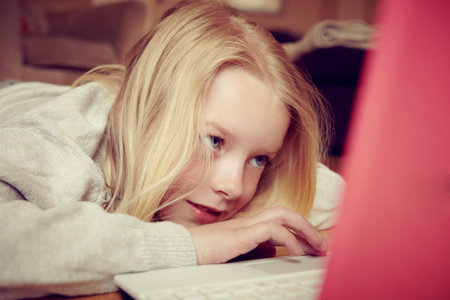 Young Girl Lying On Floor Using Laptopの写真素材