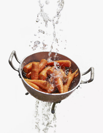 Water Falling Through Colander With Fresh Carrotsの写真素材