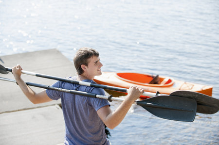 Young Man Holding Canoe Oars On Shouldersの写真素材