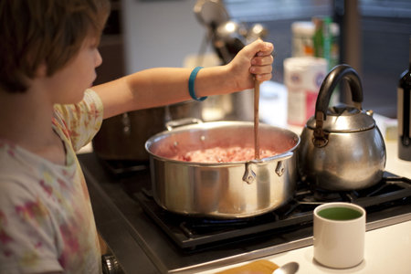 Boy Stirring Pan Of Food On Stoveの写真素材