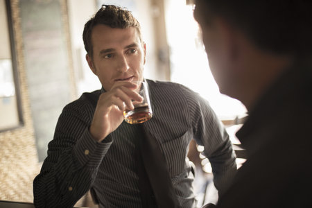 Two Businessmen Having A Drink In Wine Bar