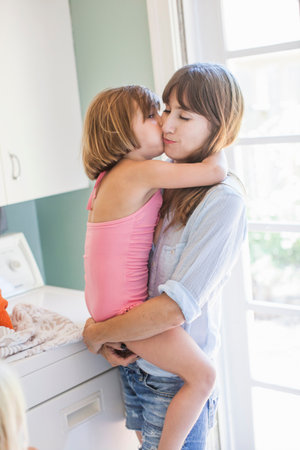 Mother And Daughter Hugging In Utility Room, Portraitの写真素材