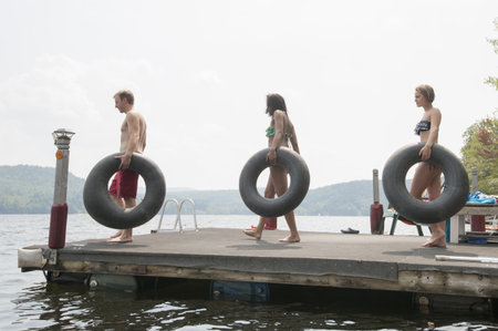 Friends On Jetty Carrying Inflatable Ringsの写真素材