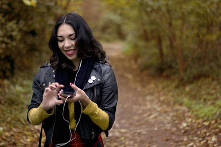 Young Woman In Park, Listening To Music Using Earphonesの写真素材