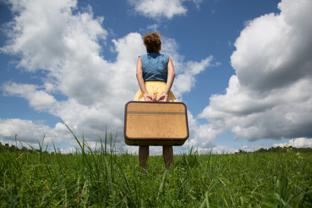 Teenage Girl Holding Suitcase In Fieldの写真素材