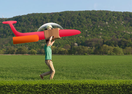 Man Running With Child In Model Airplane Across Fieldの写真素材
