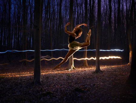 Female Dancer Jumping Mid Air In Darkened Forestの写真素材
