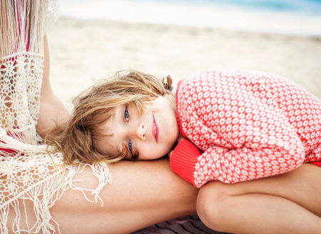 Child Looking At Camera Resting Head On Mother's Thighの写真素材