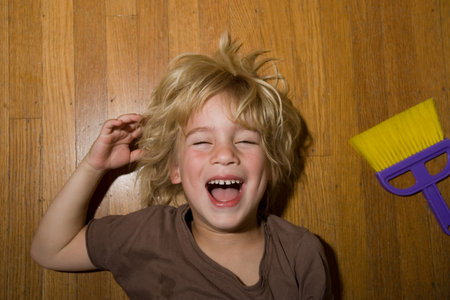 Boy Lying On Wooden Floor Laughingの写真素材