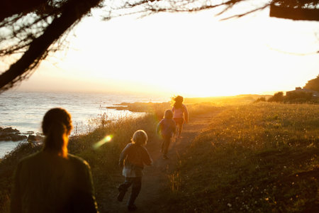 Family Walking By Coast At Sunset
