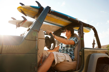 Teenager Driving Jeep With Surfboardsの写真素材