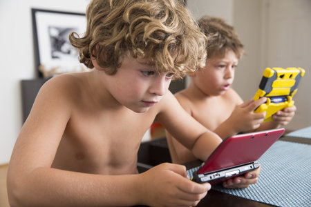 Boys Playing With Portable Game Consoleの写真素材