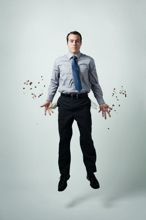 Businessman With Coins Coming Out Of His Pocketsの写真素材